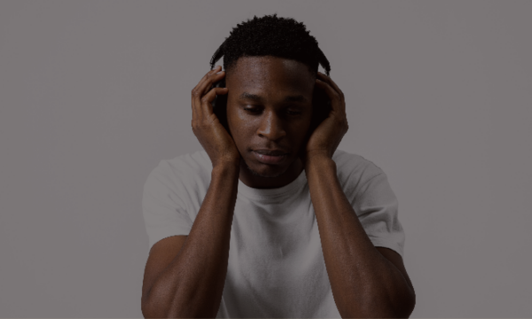 Rapper-with-his-head-in-his-hands-holding-headphones-to-his-ears-while-stressed-out